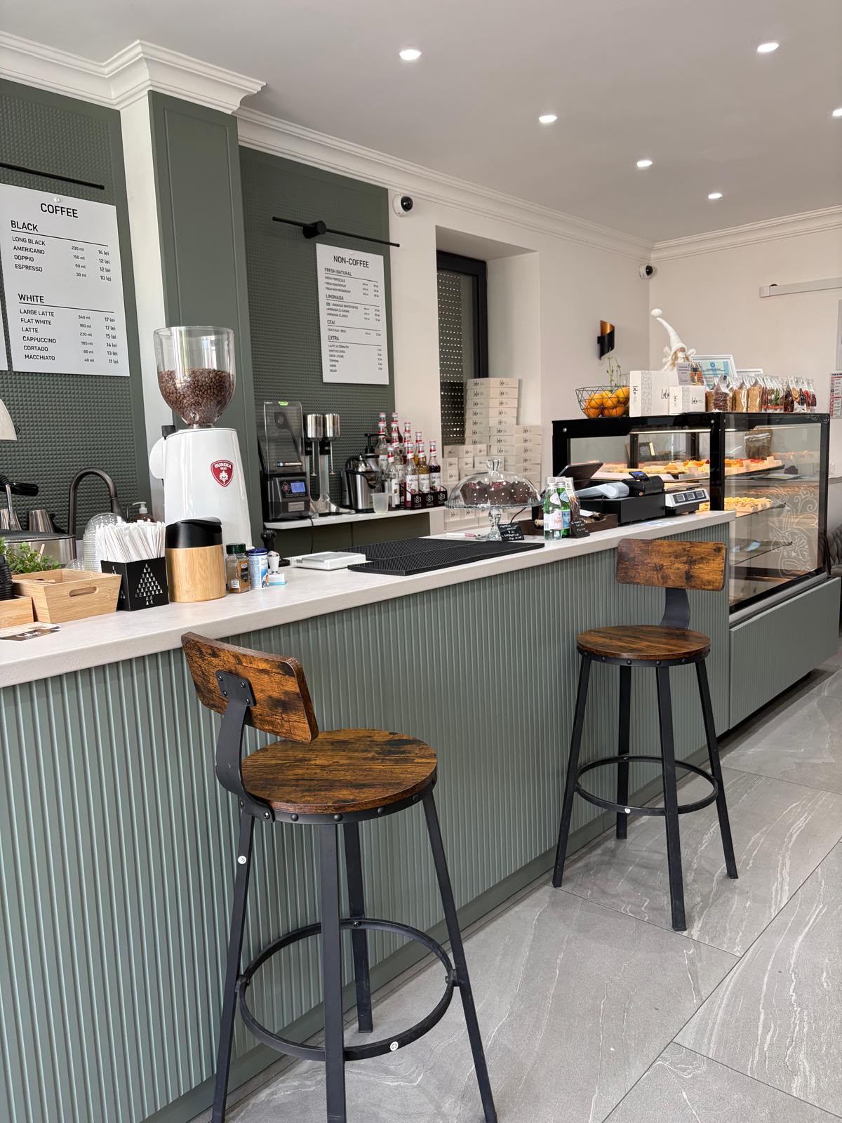 Barul cafenelei, cu espressor, râșniță și două scaune înalte la tejghea